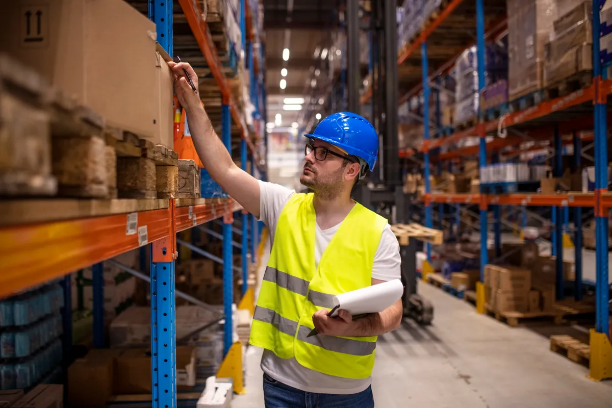 Profissional de armazém com equipamento de proteção segurando checklist para conferência de inventário