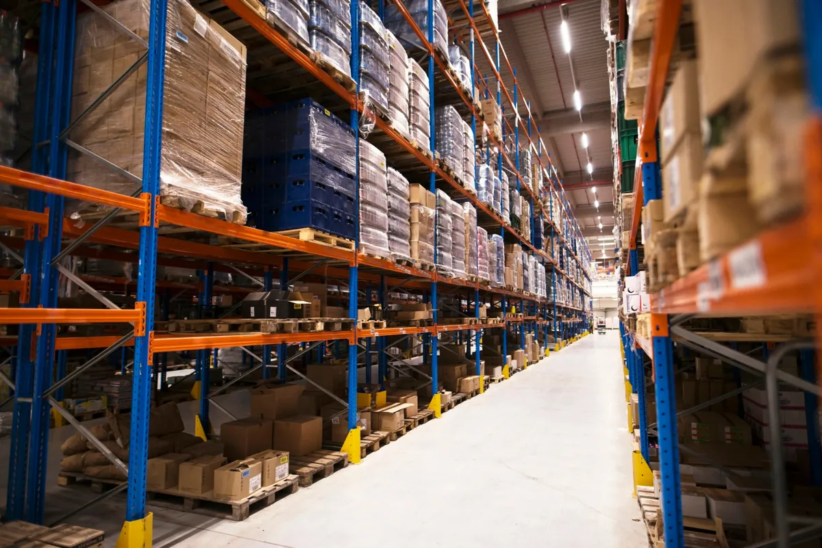 Interior de armazém de distribuição com prateleiras altas organizadas por paletes de mercadorias